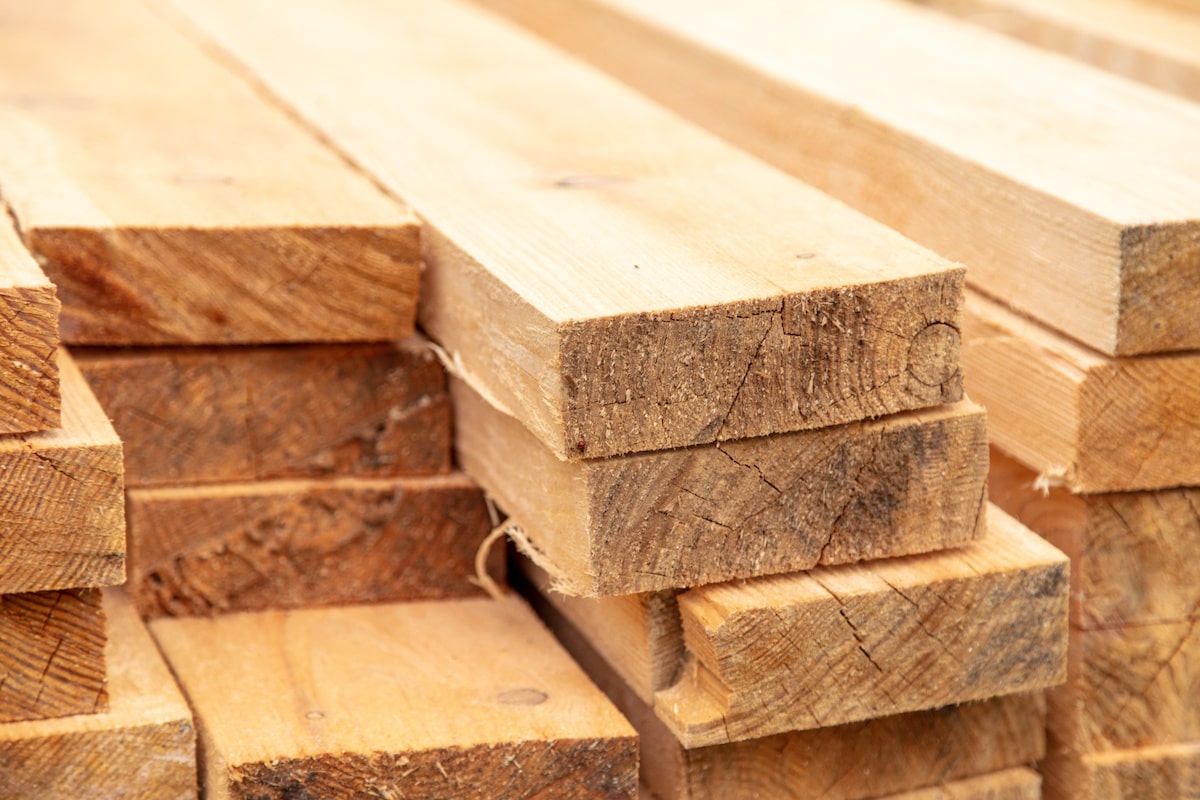 Many boards of lumber lay in a stack.