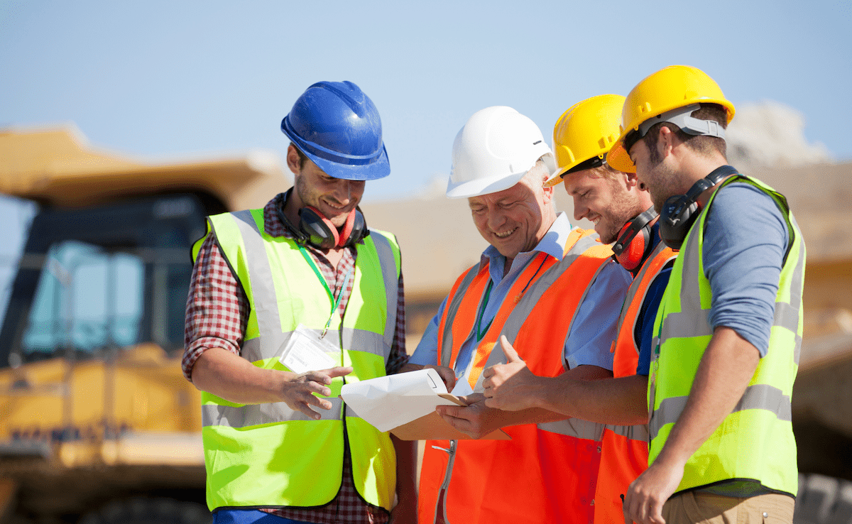 Group of smiling home builders wearing hard hats on a construction site