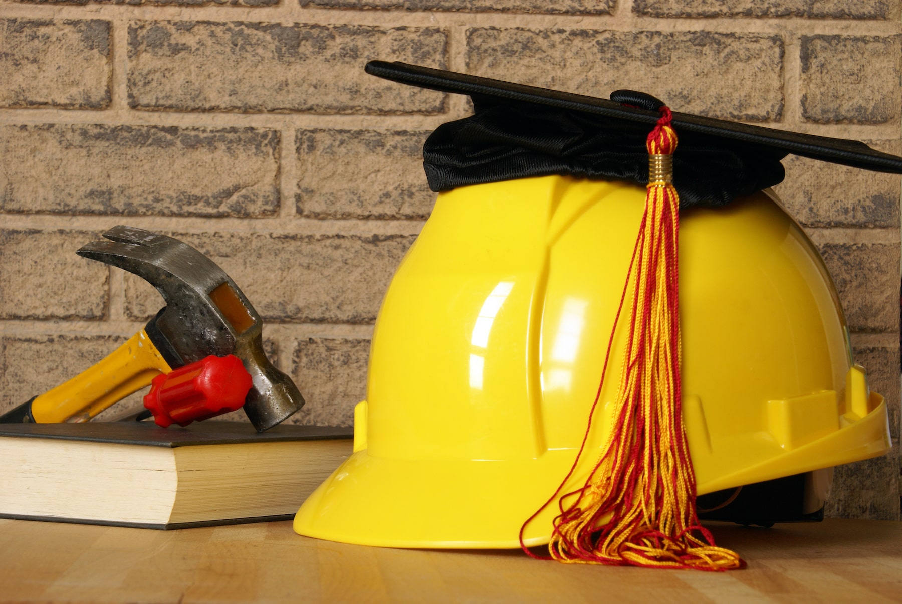 Hammer, books, hard hat and graduation cap