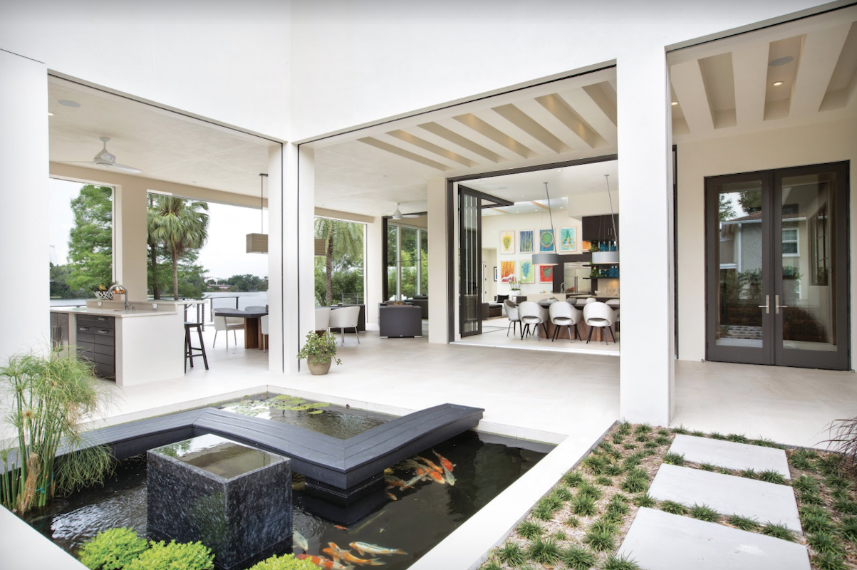 Modern home outdoor living space with large openings, summer kitchen, and koi pond