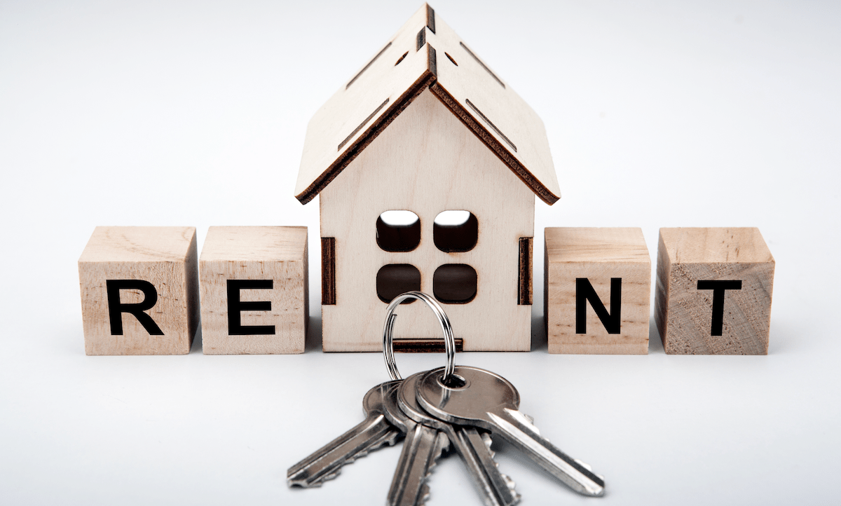 Wooden house model with house keys and RENT letters on wood blocks