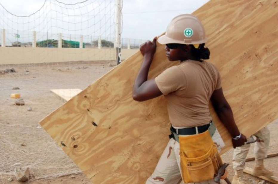 Woman with hard hat carrying plywood