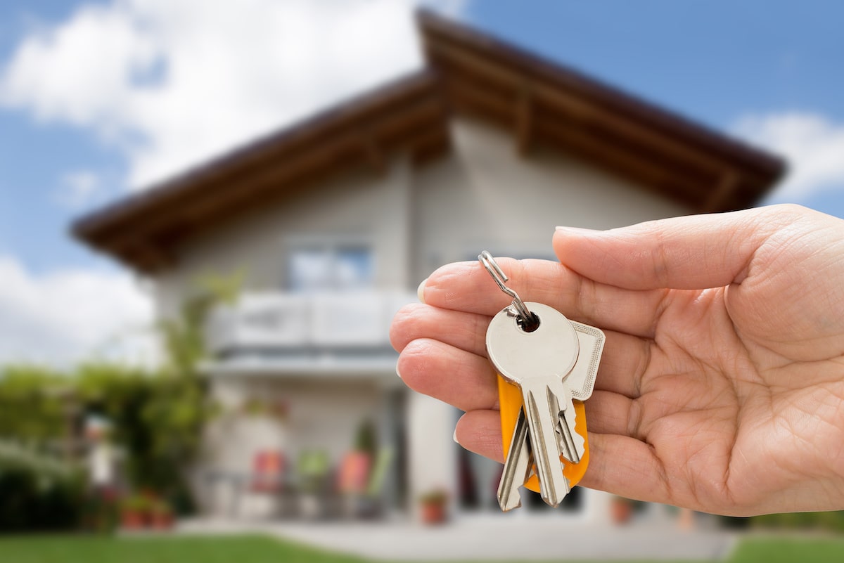 New homebuyer holds keys in front of house