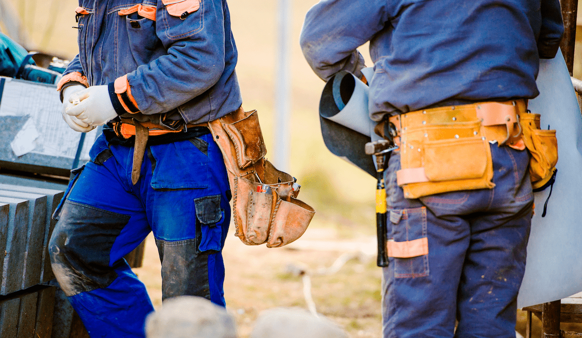 Two construction workers on jobsite wearing toolbelts