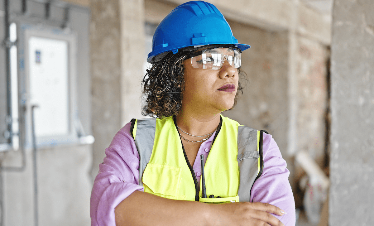 Woman in blue hard hat and yellow safety vest on construction jobsite