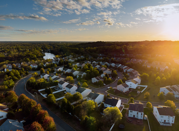 aerial view of homes in a neighborhood with sun rising over hill