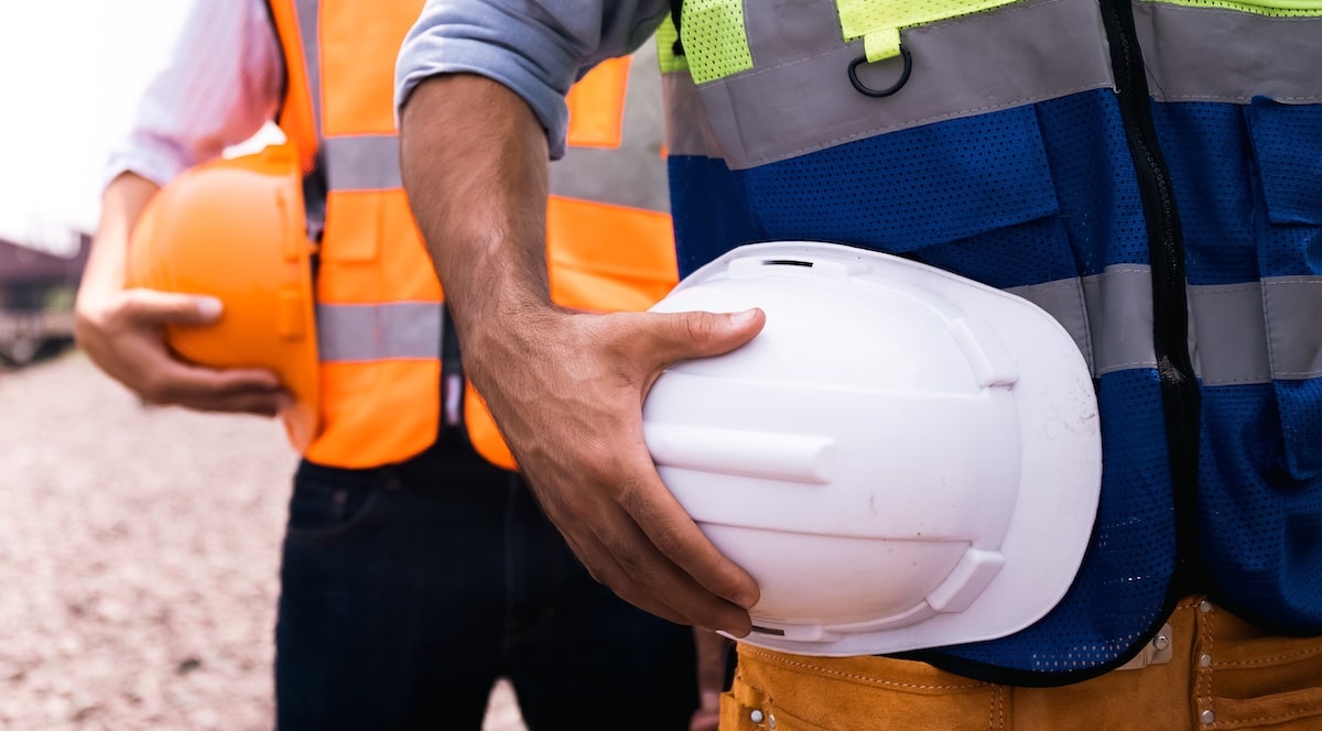 Builders in fluorescent vests holding hard hats 