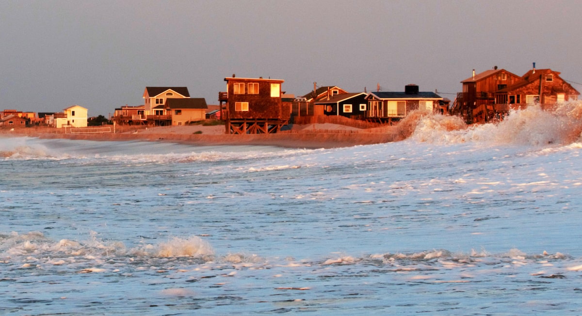 View of coastal homes at sunset from choppy sea