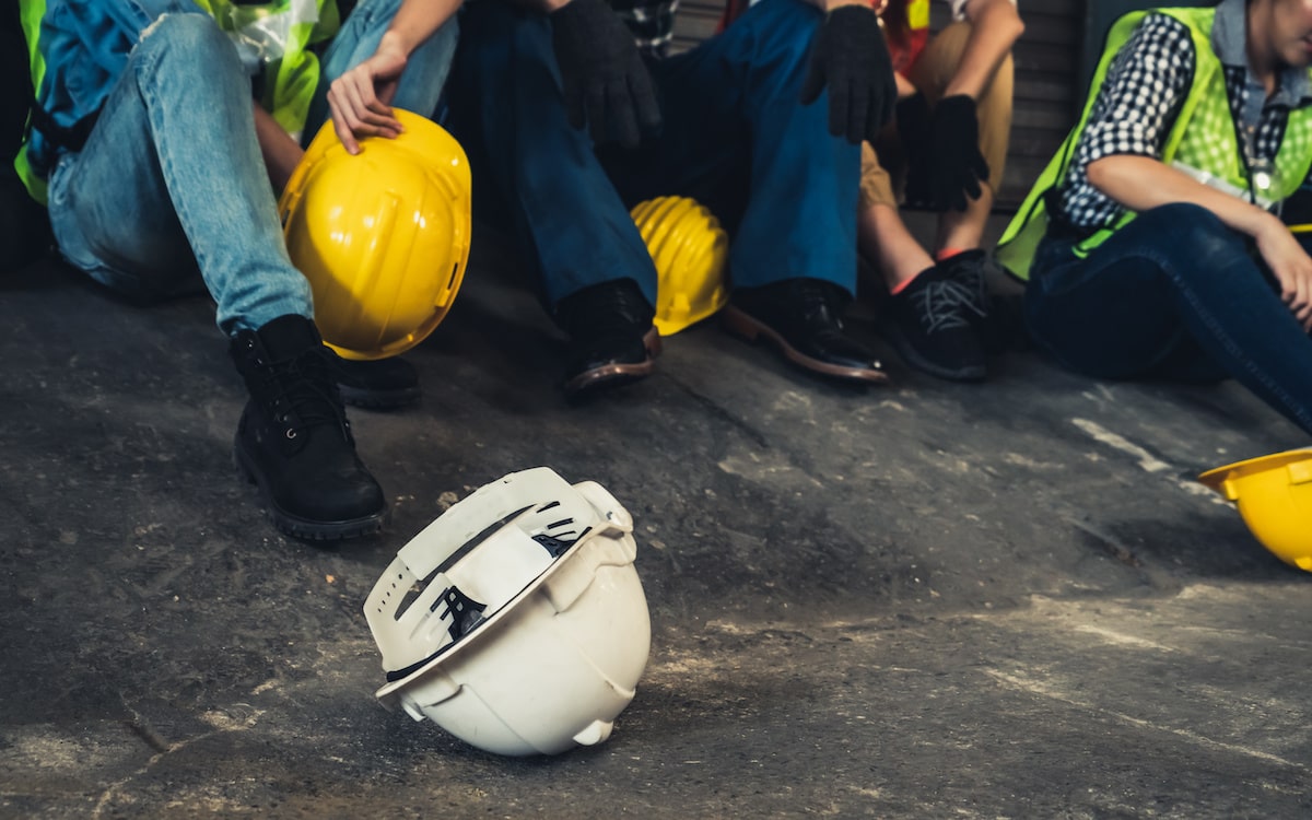 White hard hat on ground next to group of construction workers sitting down