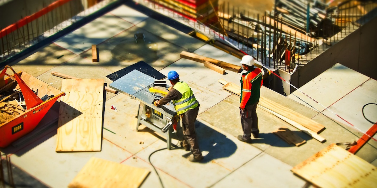Construction workers cutting plywood panels on jobsite 