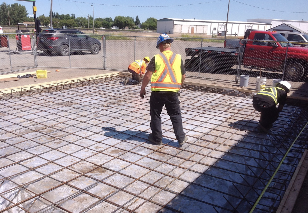 Construction worker inspects concrete slab for new home construction