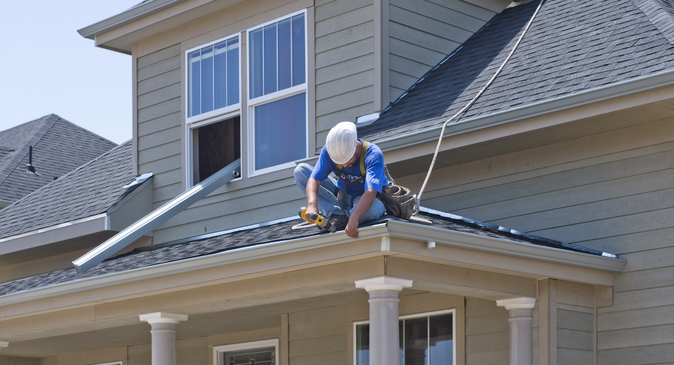 Construction worker on roof installing gutter in Denver on net zero energy ready new home