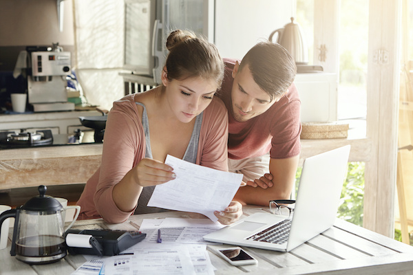 young couple looking over bills at kitchen table
