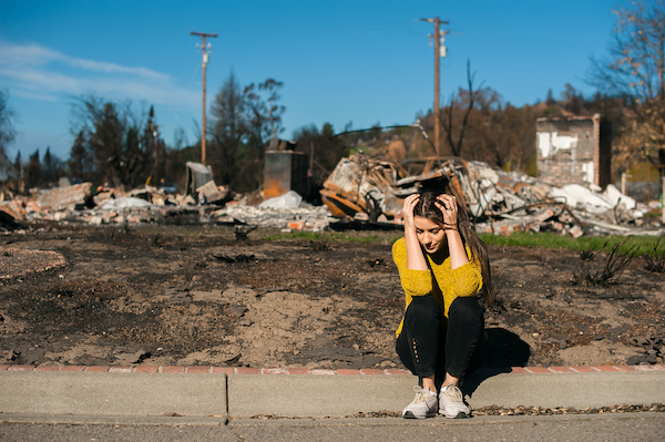Woman at disaster site with hands on head