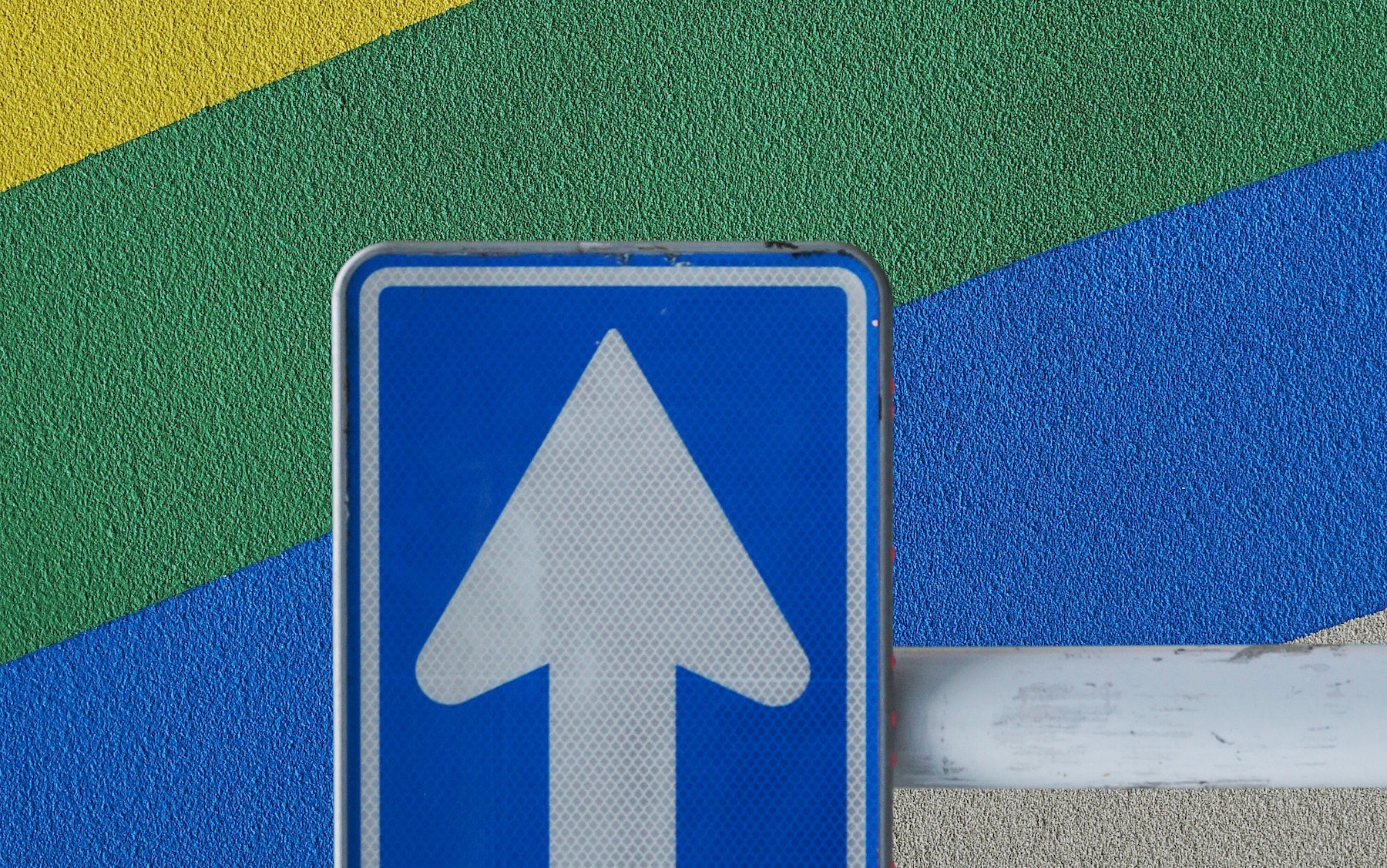 Up arrow sign against rainbow cement wall