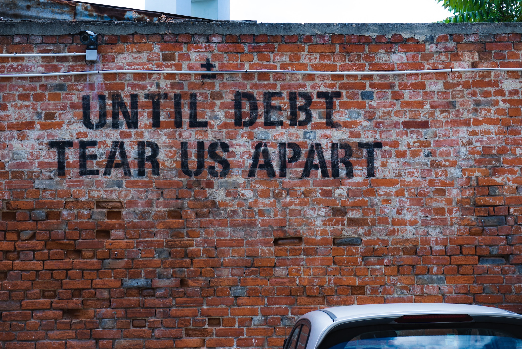 Mural 'until debt tear us apart' on brick wall