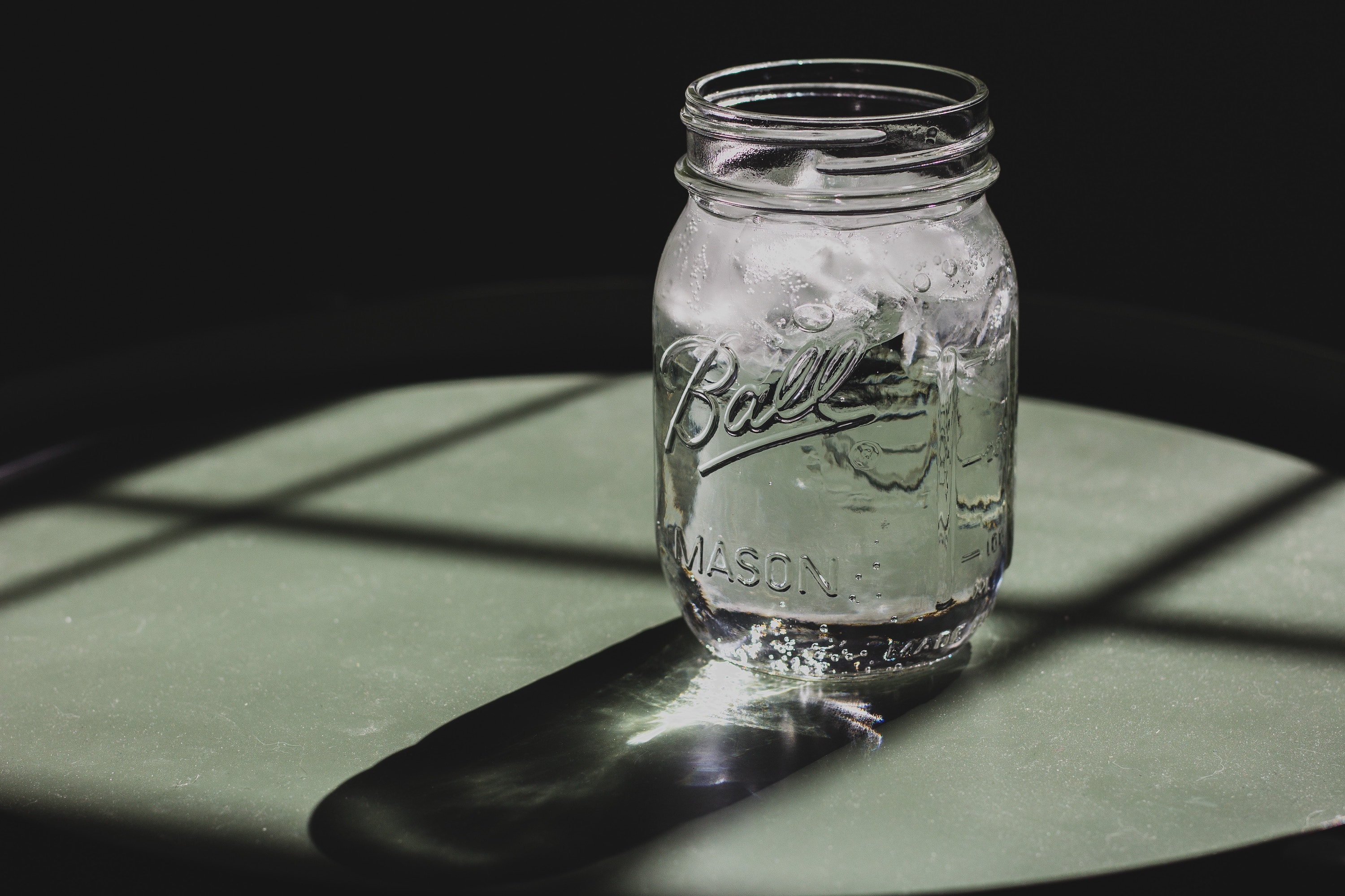 Mason jar with ice water in it on table