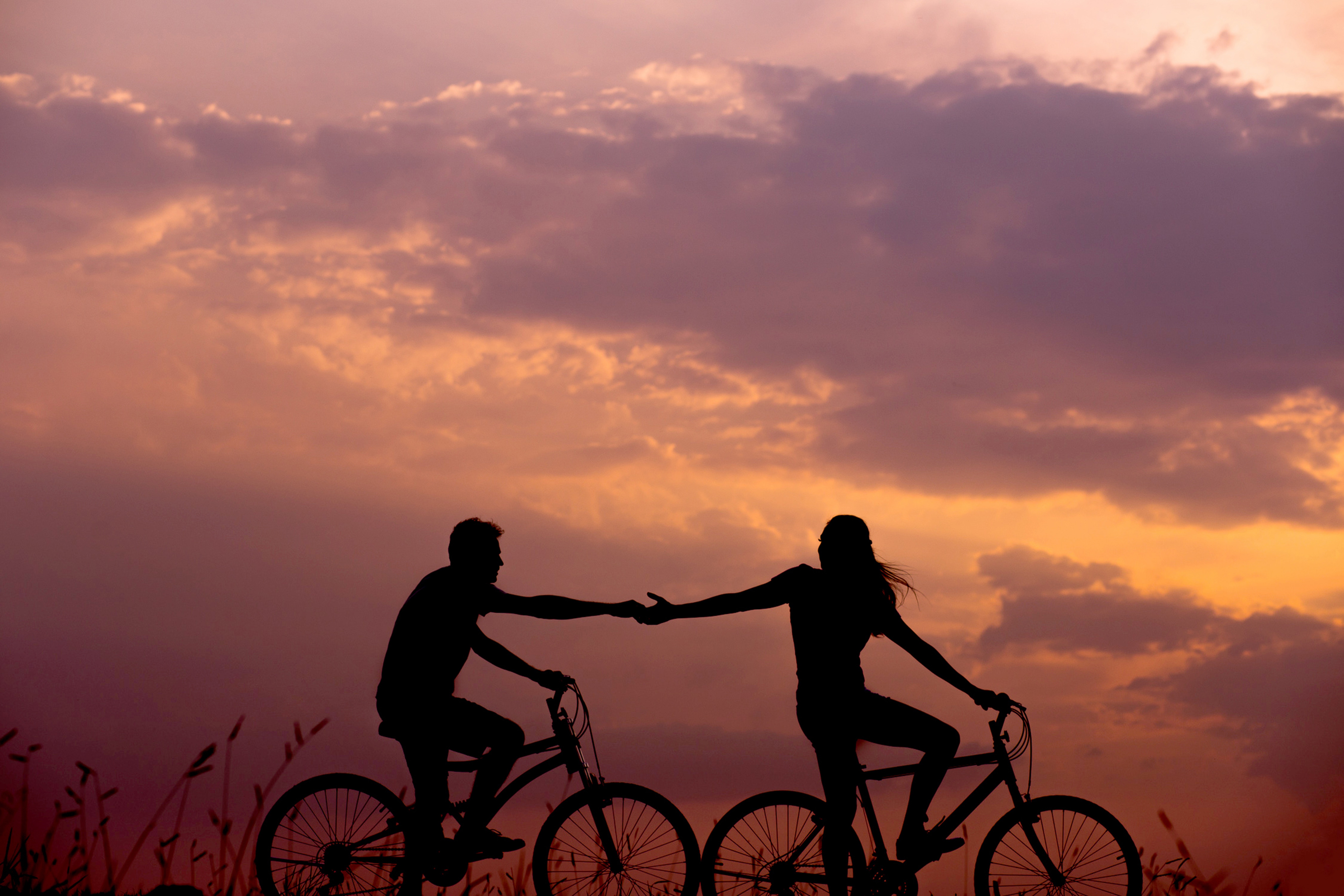 Couple riding bikes, holding hands