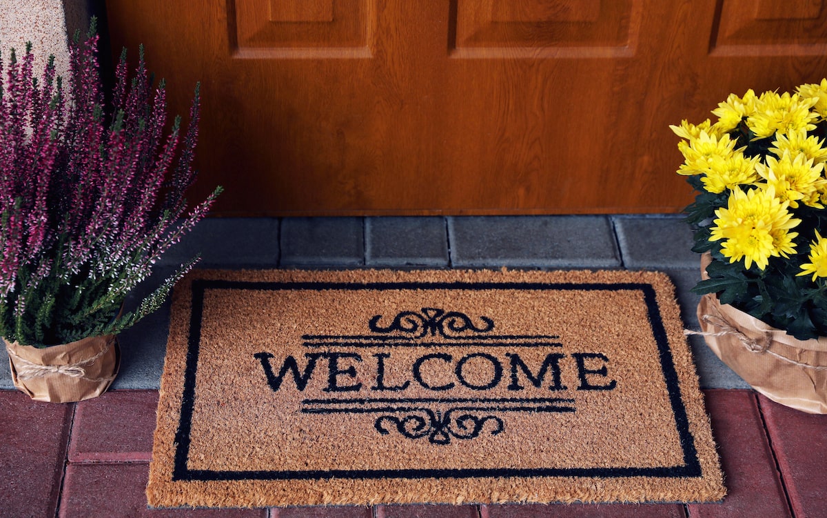 Welcome mat and flowers on house doorstep