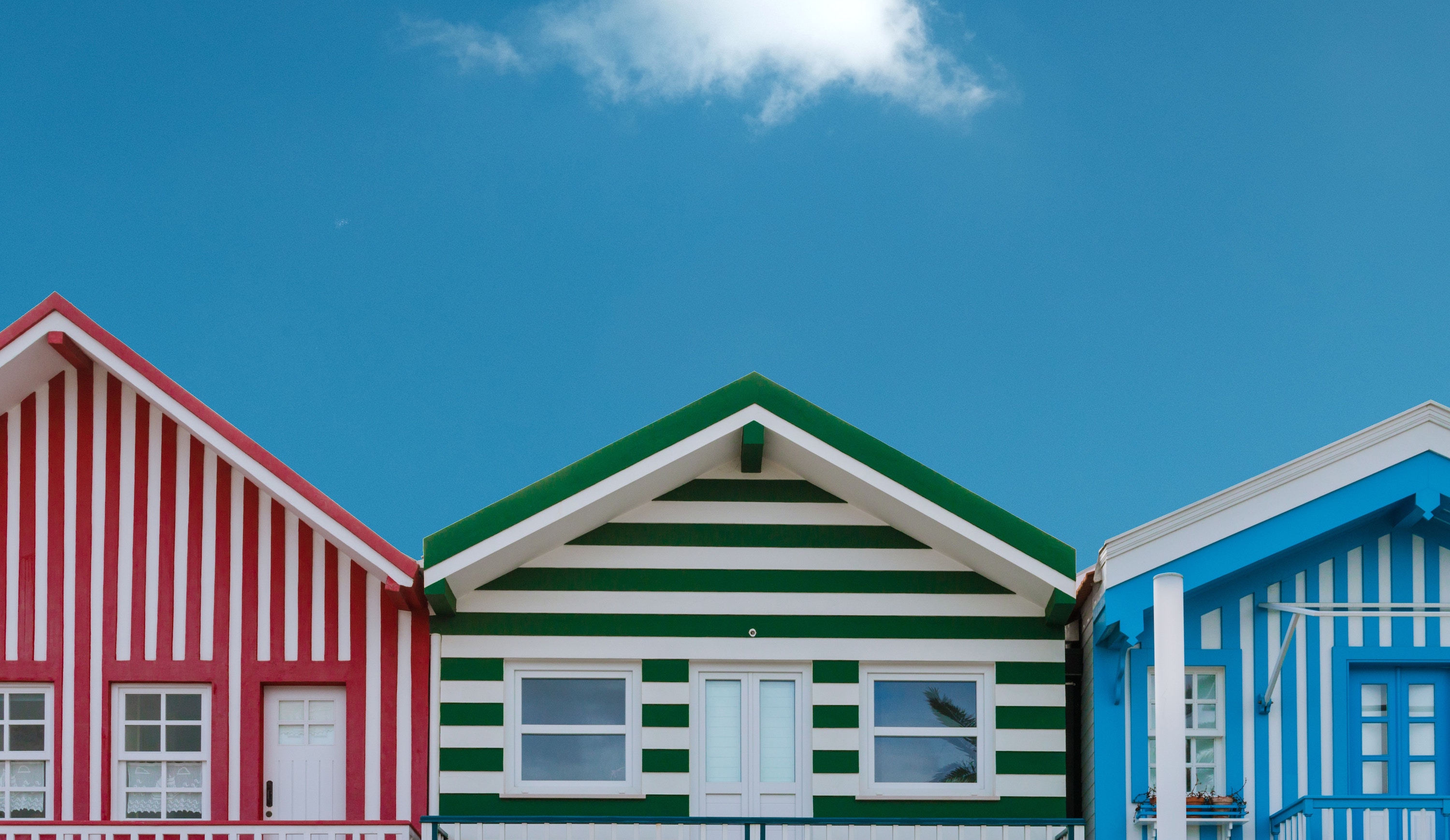 Three striped houses against a blue sky