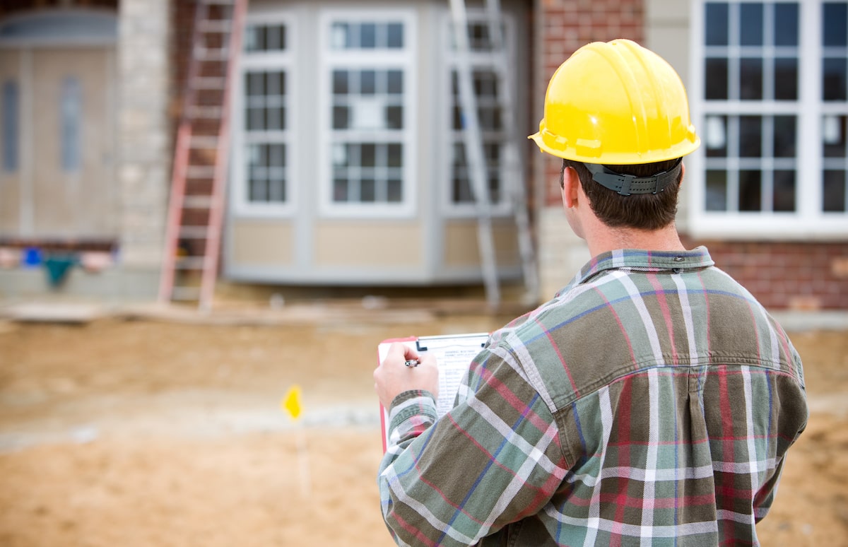 Home builder standing in front of house under construction