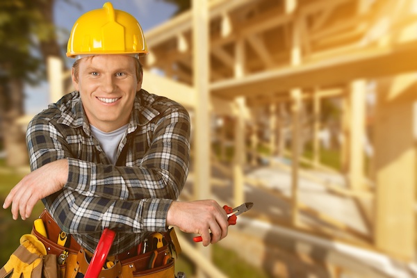 home builder leaning on tools in front of framing