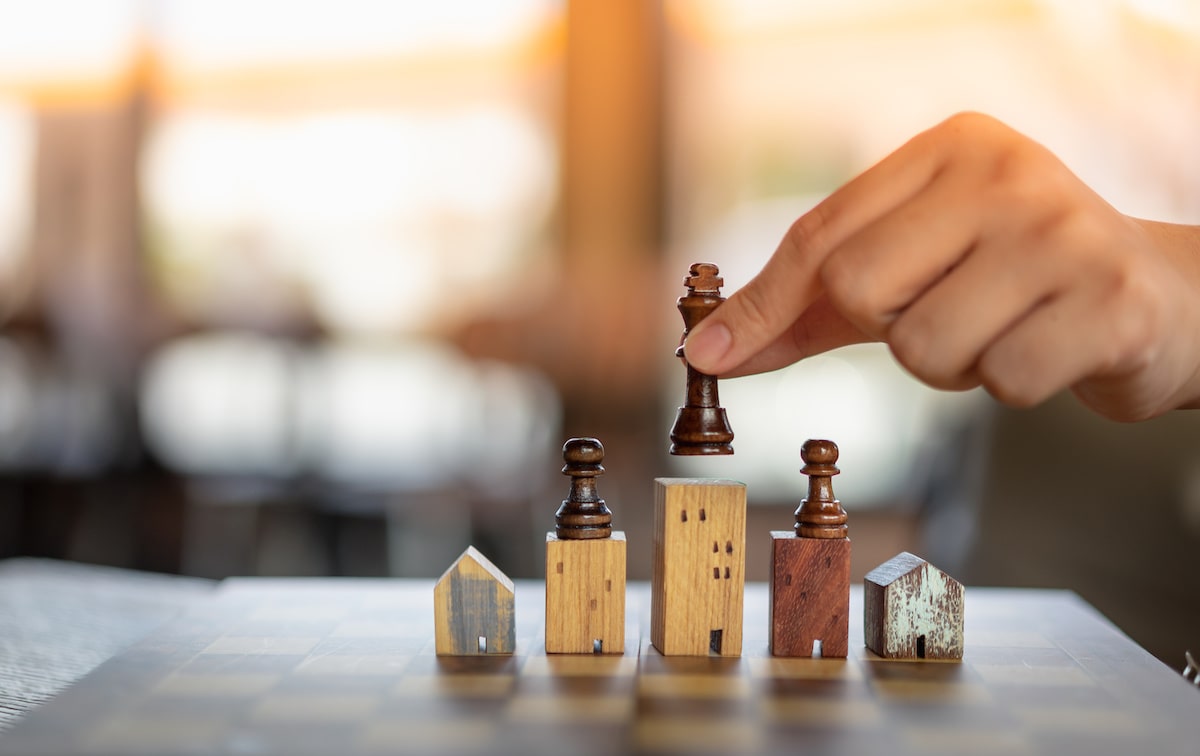 Model houses on chess board with players placed on top of pieces