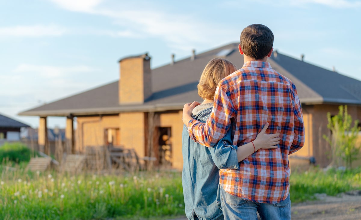 Homeowners hugging and standing outside of home