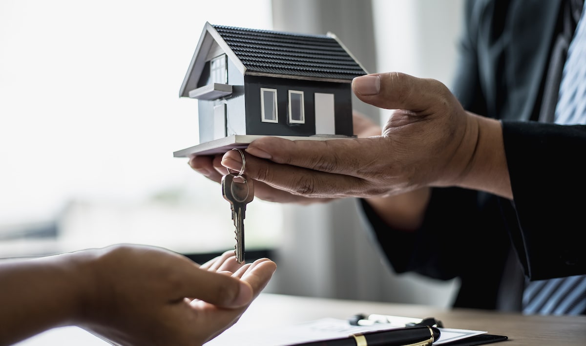 Home seller handing home model and house keys to buyer