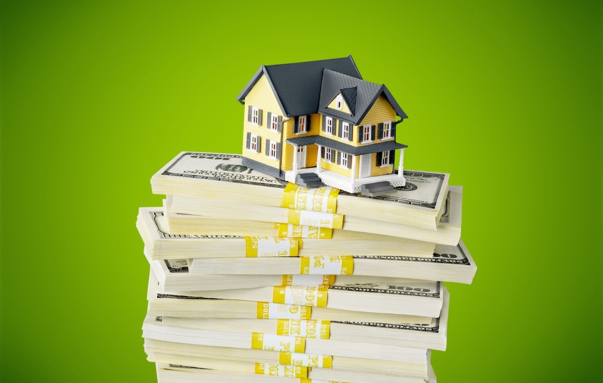 House on top of stacks of cash with green background