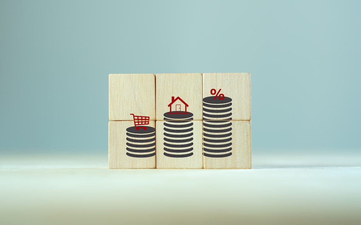 House, shopping cart, and percentage stacked on coins displayed on wooden blocks 