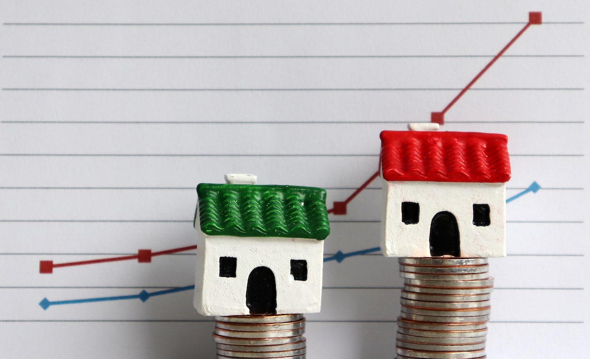 Houses on uneven stacks of coins against line graph