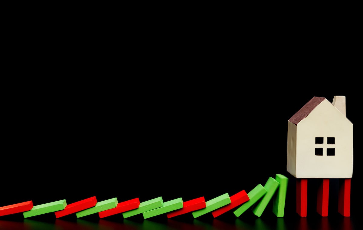 Red and green dominoes falling into small house with black background