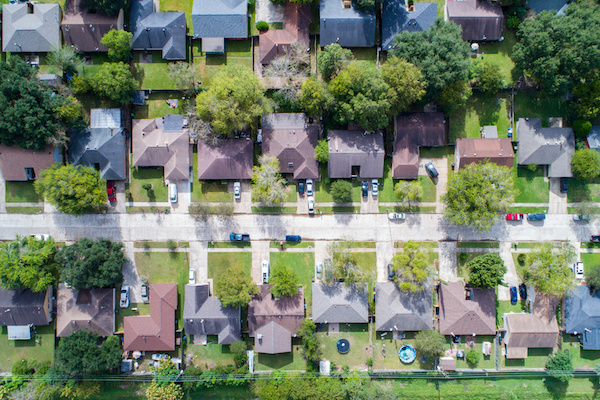 aerial view of homes with trees and green front and back yards
