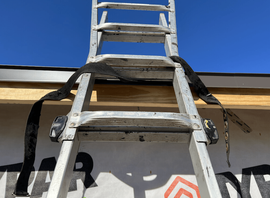 To safely use an extension ladder, secure the top of the ladder with an approved strap to prevent it from moving when in use.