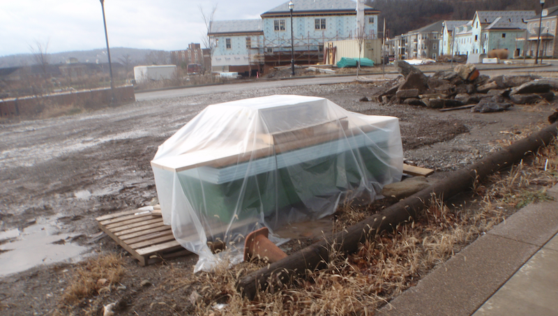 muddy jobsite with materials stored correctly off the ground and covered with plastic tarps