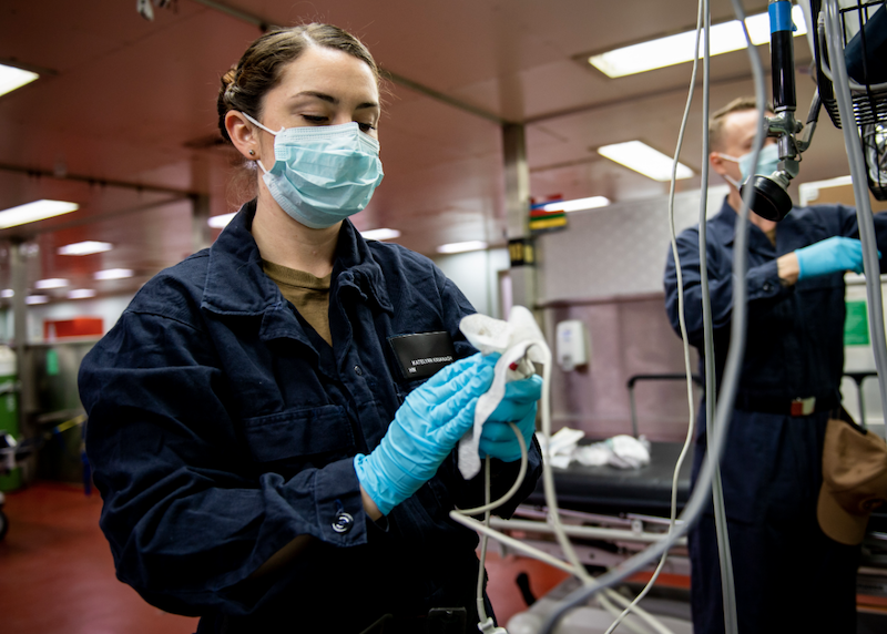 woman wearing protective mask sanitizes medical equipment during coronavirus pandemic
