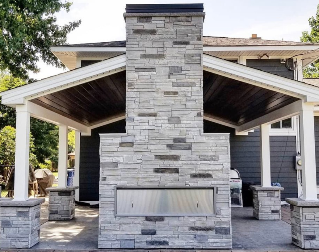 Versetta Stone panelized stone siding offers an easy way to dress up outdoor fireplaces for a truly cozy space. Switala-Berner Construction crafted this two-sided unit with Ledgestone in Mission Point.