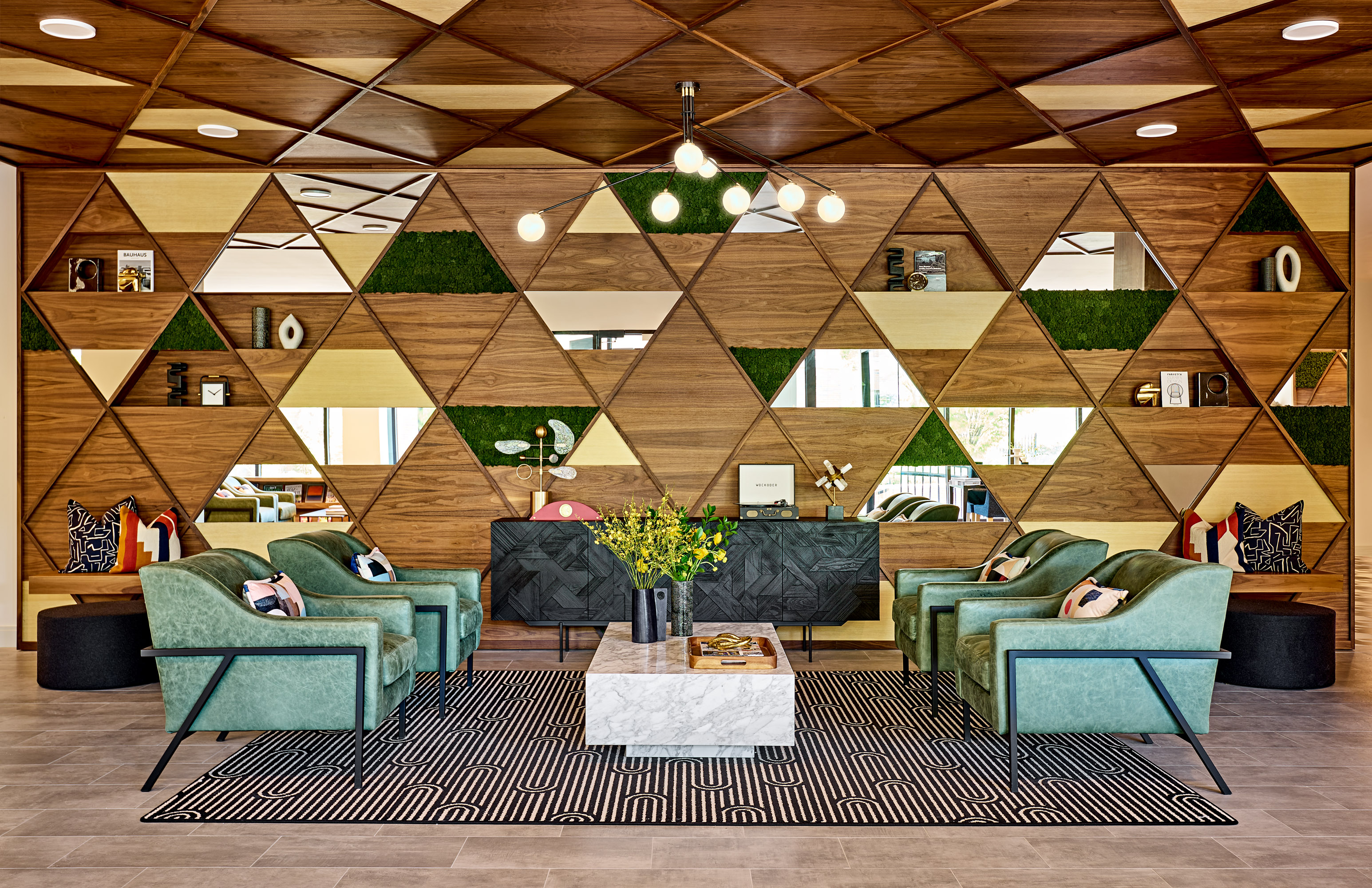 Soothing emerald toned lounge chairs contrast the bold backdrop in this main entry lobby to elevate the impact at arrival.