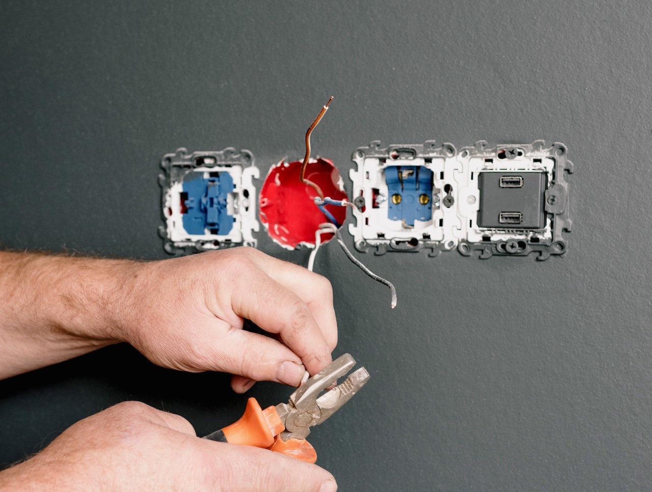 An Electrician Using Pliers to Repair the AC Power Plugs and Sockets