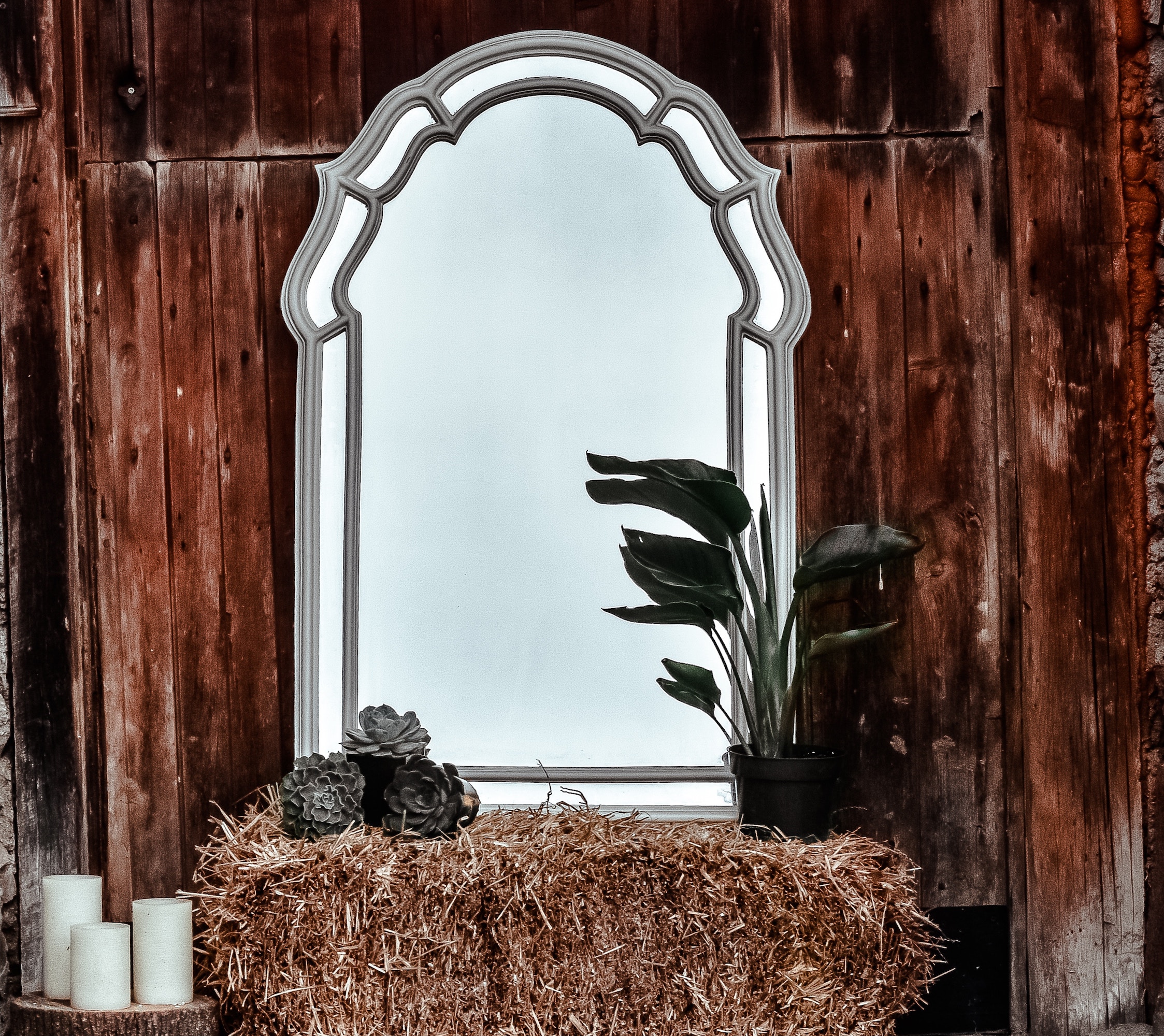 Mirror on hay bale with candles and plants