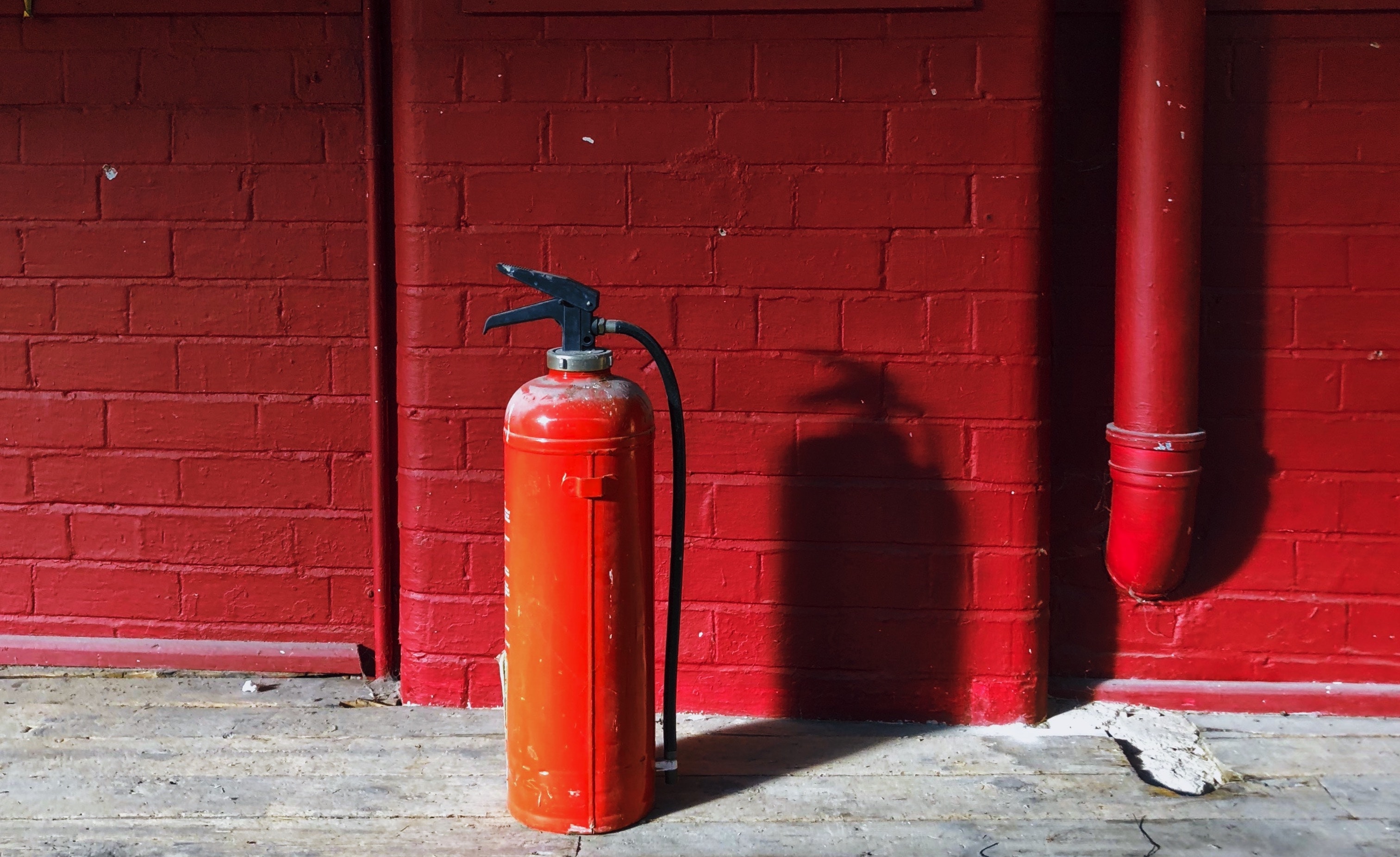 Fire extinguisher on floor against red wall