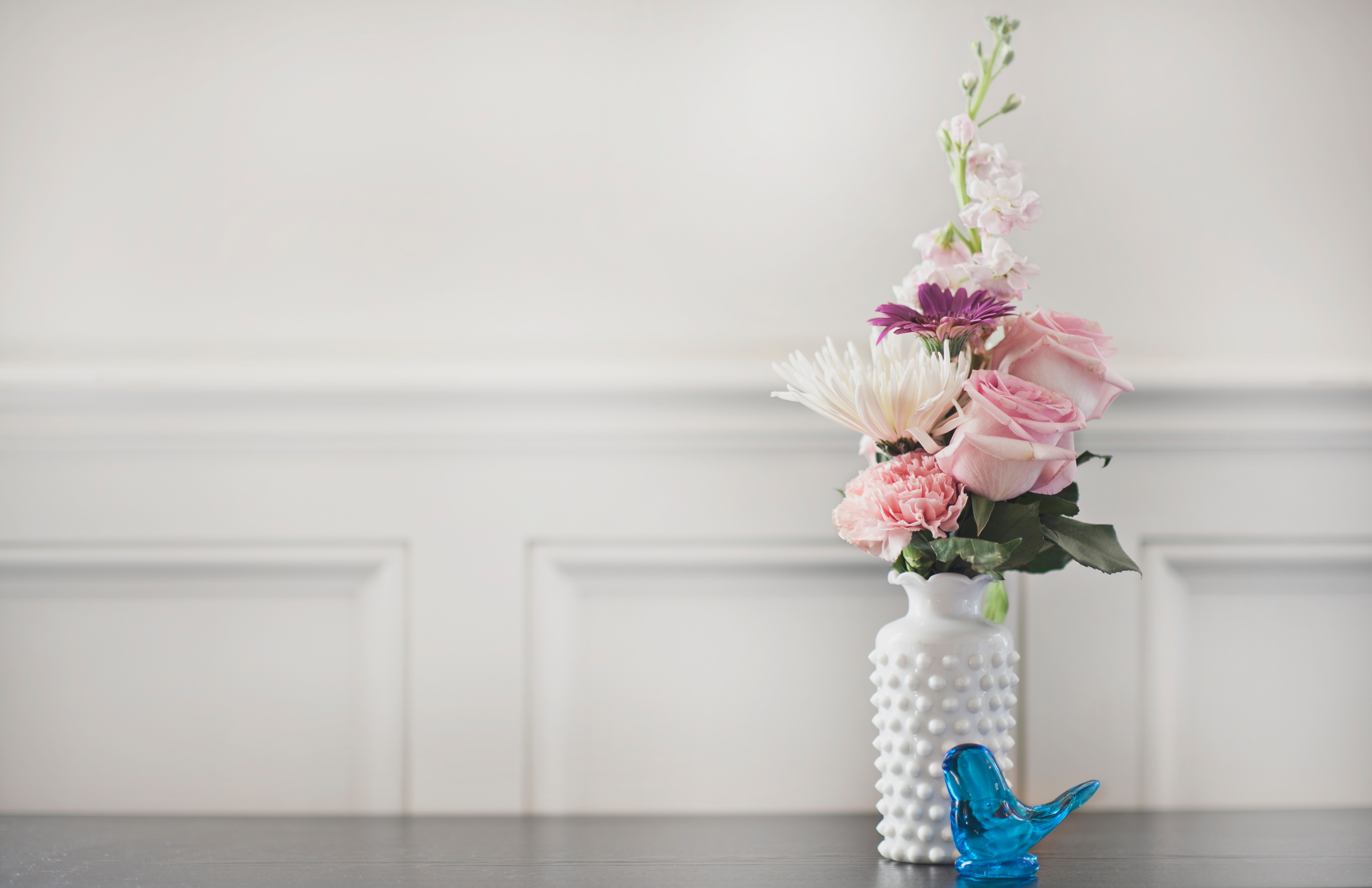 Bouquet of flowers in vase on table with blue bird
