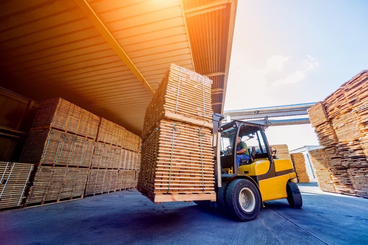 Lumber is carried through a warehouse.