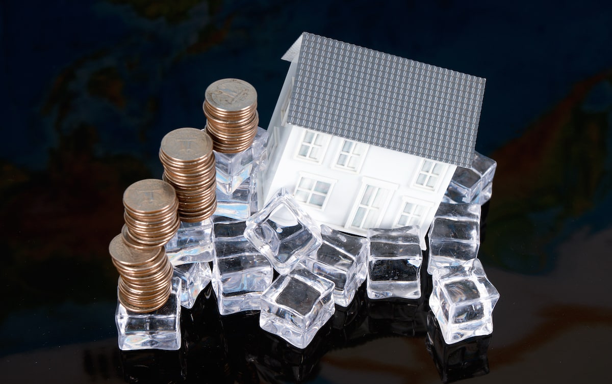 House on pile of ice next to stack of coins