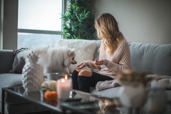 Millennial woman at home sitting on the couch with her dog