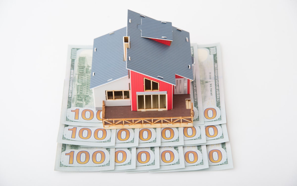 Small house replica on top of hundred dollar bills in line