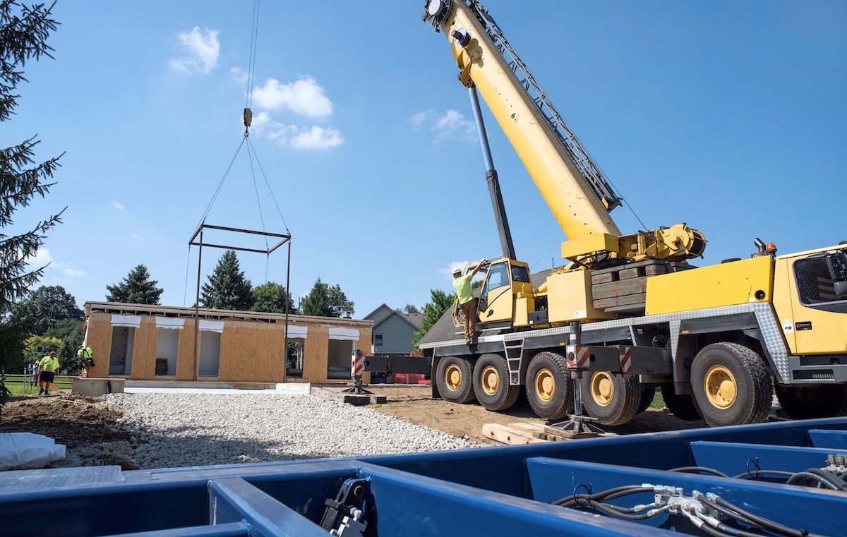 Crane transporting modular home structure to jobsite