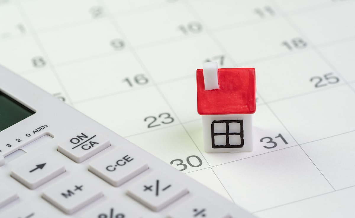 Small house and calculator on monthly calendar