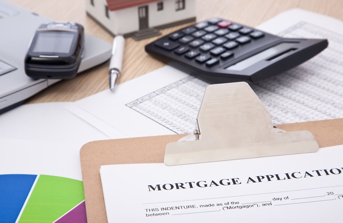 Mortgage application next to calculator and small house model